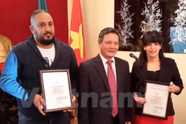 越南驻阿尔及利亚大使向阿尔及利亚记者奥吴拉·拉扎和利安德·阿巴达颁发奖状（图片来源：越通社） 