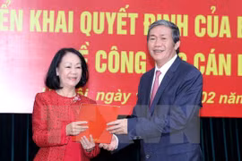 越共中央政治局委员、书记处常务书记丁世兄（右）向张氏梅女士（左）授予决定书