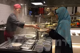 ​马来西亚游客尝试越南传统河粉（图片来源：vietnam+)