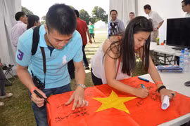 大学生共同在国旗上签字（图片来源：越通社）
