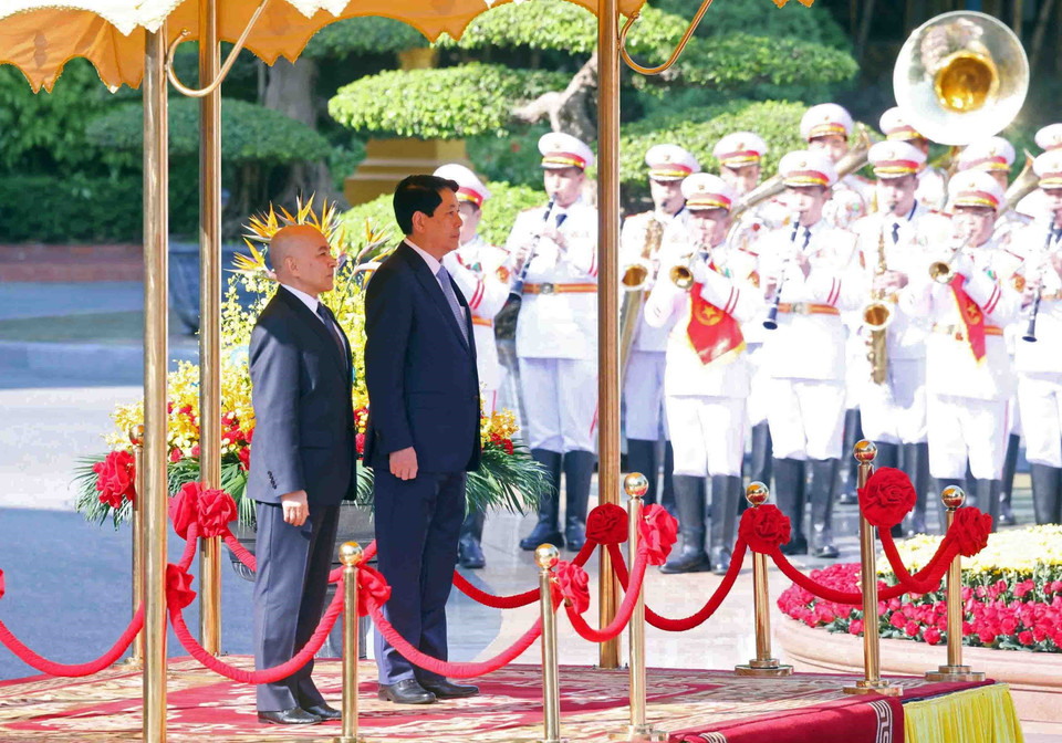 越南国家主席梁强和柬埔寨国王诺罗敦·西哈莫尼登上荣誉主席台，聆听军乐奏响两国国歌。图自越通社