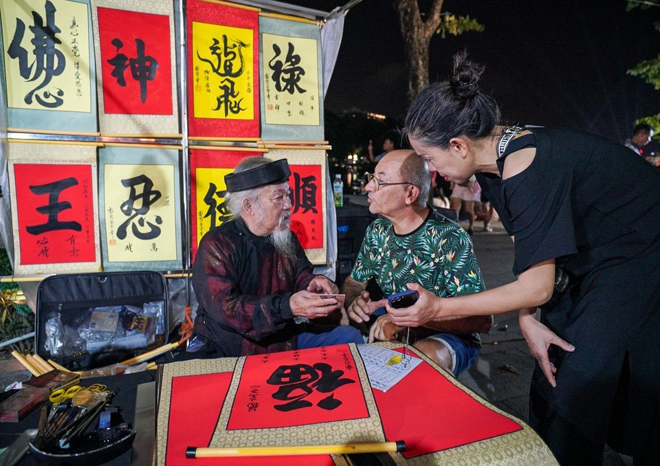 外国游客在还剑湖步行街求字。图自越通社