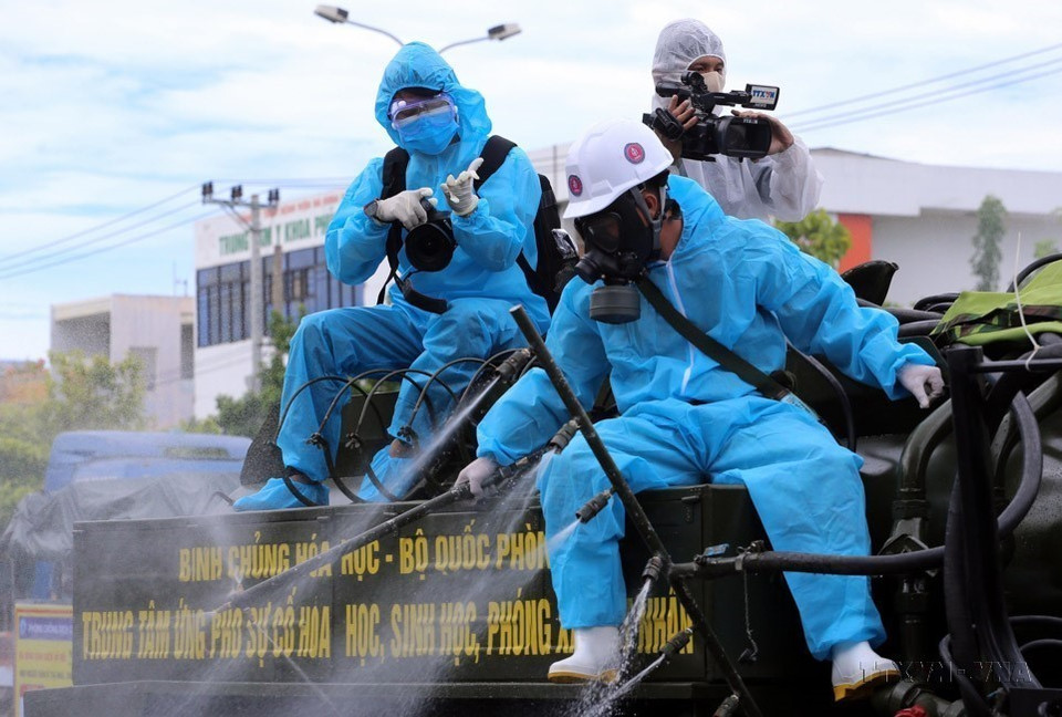 越通社电视频道记者在岘港市山茶郡新冠肺炎感染高危区域消毒车上进行新闻报道。图自越通社