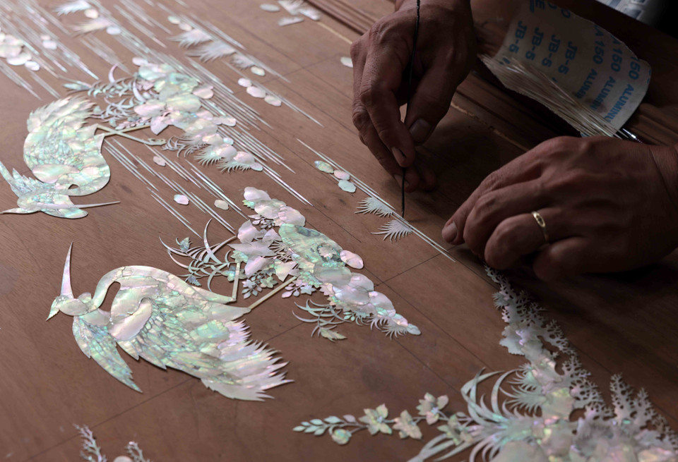 在雕刻之前将贝壳图案放置在木材上。图自越通社