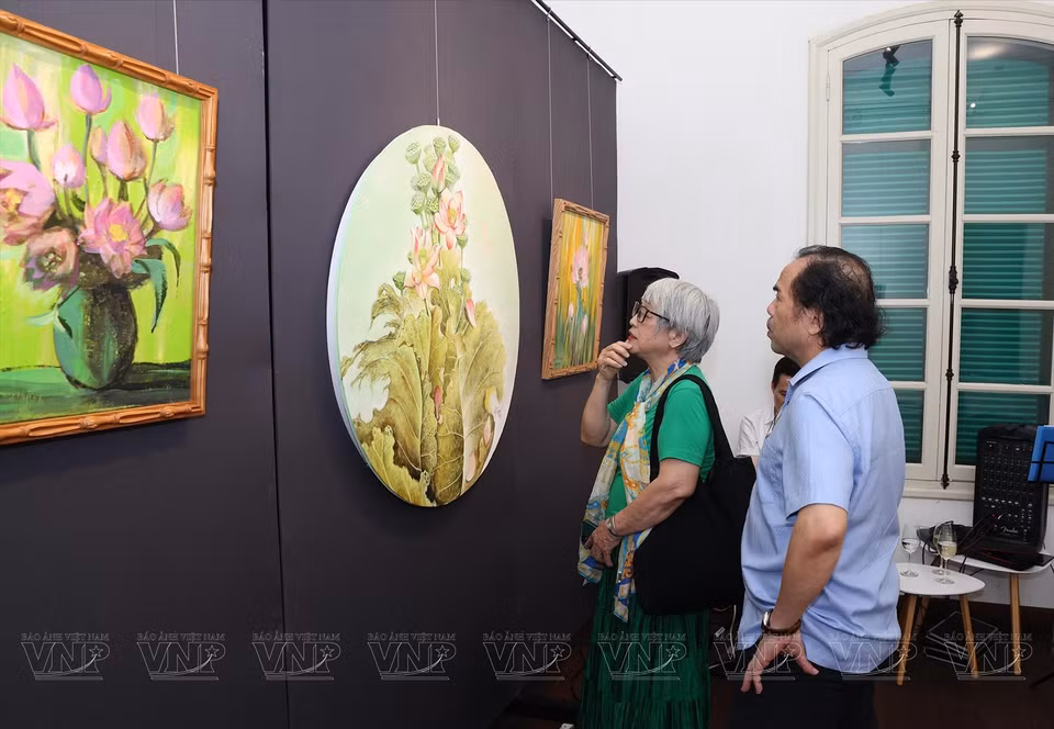 嘉宾参观并欣赏荷花画作。图自越通社/越南画报