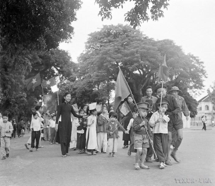 河内儿童与亲人举起国旗，欢迎部队凯旋归来，接管首都政权。图自越通社