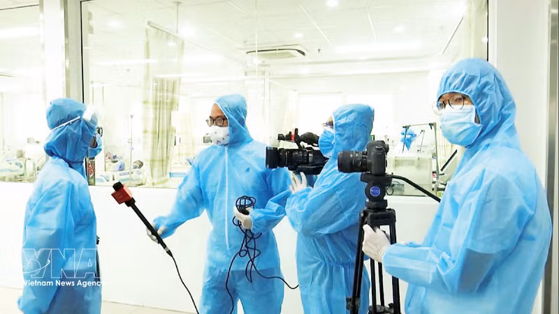新冠肺炎疫情期间在岘港市工作的记者们。图自越通社