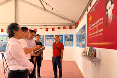 《人民报》代表向越南驻法国大使Kalamoungkhoune Souphanouvong（中）介绍有关胡志明主席和越南争取民族独立历程的展览内容。图自越通社