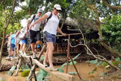外国游客在越南西部水乡体验“猴桥”，感受独具特色的乡村旅游。（图片来源：越通社）