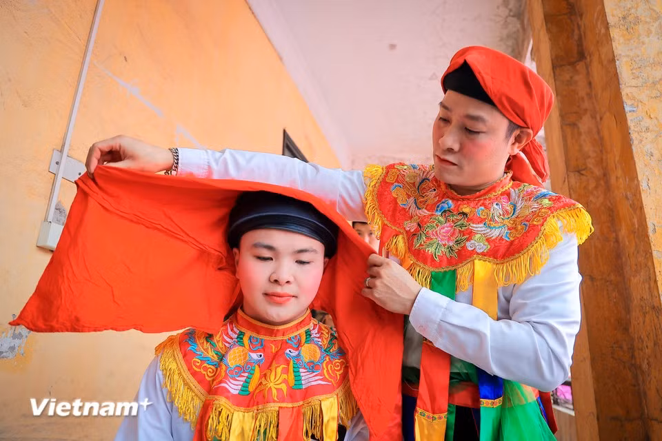 村里的少年们男扮女装，化上鲜艳的妆容，准备参加迎神轿的腰鼓舞表演。（图自Vietnam+）