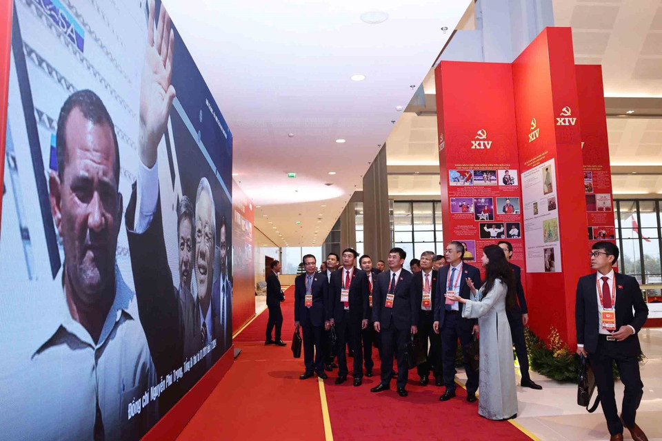 在越南共产党第十四次全国代表大会预备会议开幕前，与会代表参观了由越通社举办的《在党的旗帜下——国家迈入新时代》图片展。图自越通社