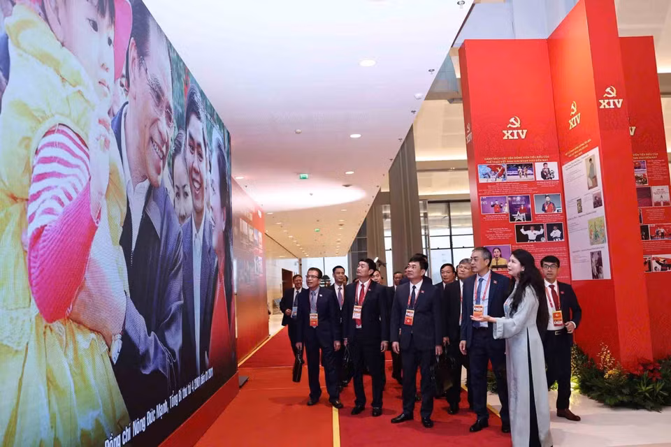 在越南共产党第十四次全国代表大会预备会议开幕前，与会代表参观了由越通社举办的《在党的旗帜下——国家迈入新时代》图片展。图自越通社