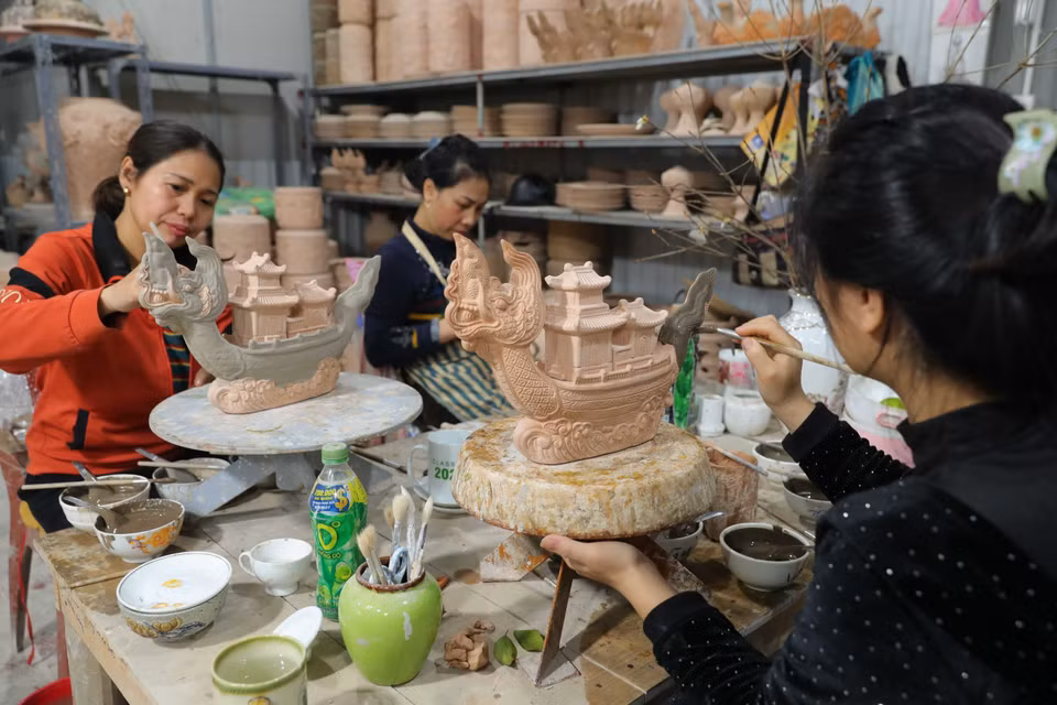 钵场陶瓷村工匠阮仲义在工厂里为陶瓷作品“御龙庆典”上釉。图自越通社