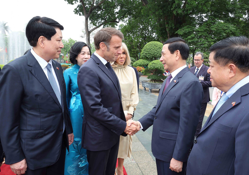 法国总统马克龙与越南代表团成员握手。图自越通社