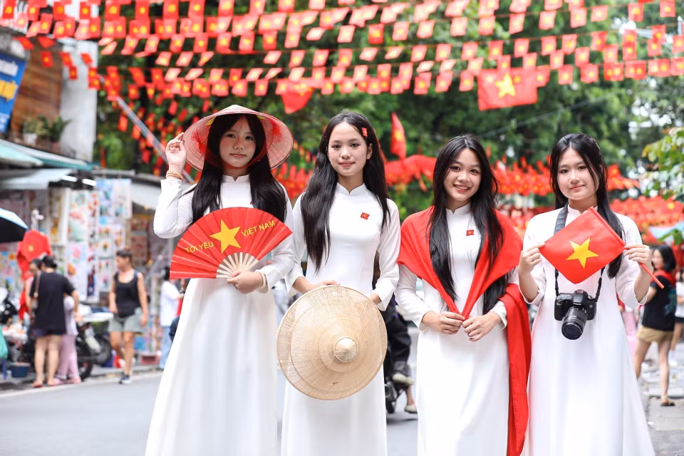 众多市民在还剑坊行马街与祖国旗帜合影留念。图自越通社