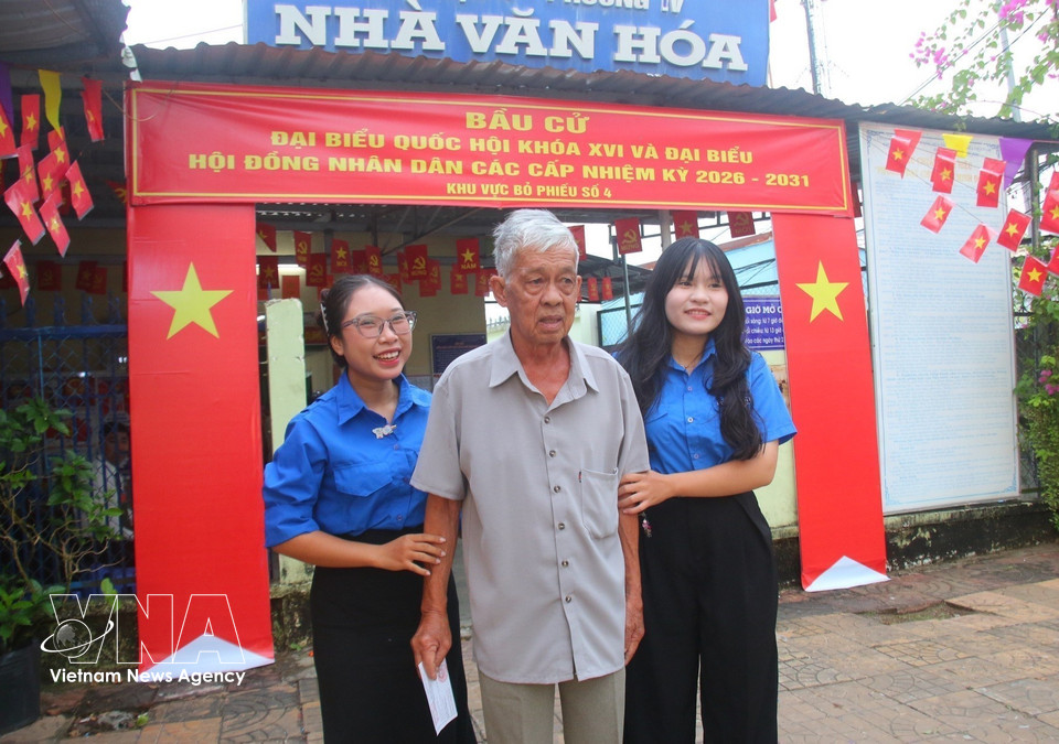 胡志明共青团青年志愿者在芹苴市味新坊第四号投票站协助年长选民参加投票。图自越通社