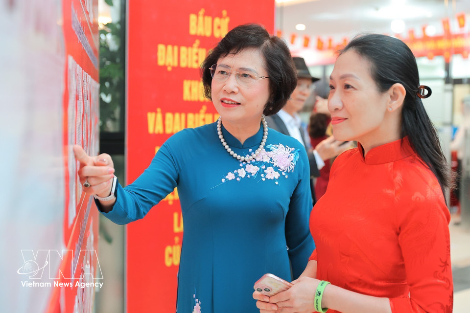 河内大穆坊第十六号投票站的选民在投票前查看候选人名单。图自越通社