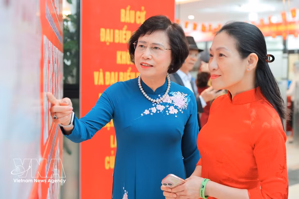 河内大穆坊第十六号投票站的选民在投票前查看候选人名单。图自越通社