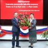 老挝人民革命党中央宣训部副部长薇拉翁·潘塔冯向越南驻老挝大使阮明心送花。图自越通社