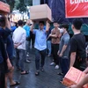 志愿者们正忙碌地将80吨物资和生活必需品装上救援车辆，送往灾区。图自越通社