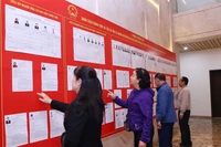 人们在河内第十三号选举单位查看候选人名单。图自越通社