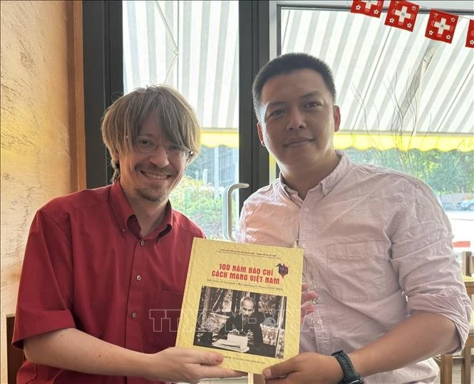 越通社记者向瑞士共产党总书记马西米利亚诺·阿伊赠送礼物。（图片来源：越通社）
