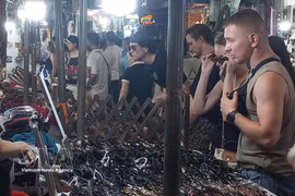 国际游客在河内古街夜市选购纪念品。图自越通社