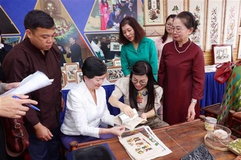 越南政府总理夫人同河内市东盟妇女小组体验东湖民间画印制。图自越通社