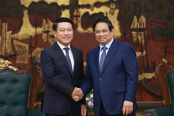 越南政府总理范明政与老挝副总理、人民革命党中央企业改革委员会主任沙伦塞·贡马西合影。越通社