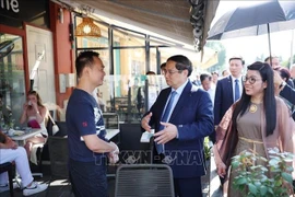 范明政总理与在尼斯市做生意的越侨亲切交谈。图自越通社