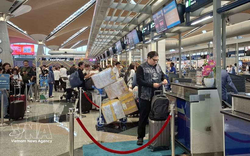 旅客在吉隆坡国际机场票务柜台办理手续。图自越通社