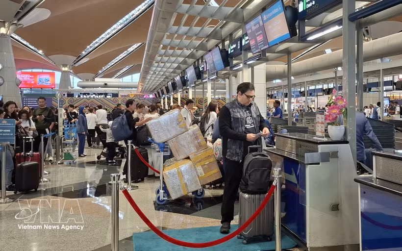 旅客在吉隆坡国际机场票务柜台办理手续。图自越通社