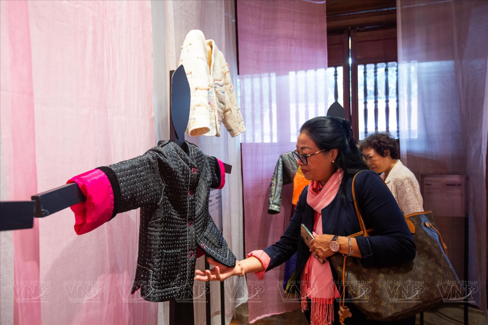 游客正在欣赏采用黑丝绸布料制作的“米粒” 绗缝棉衣。图自越通社