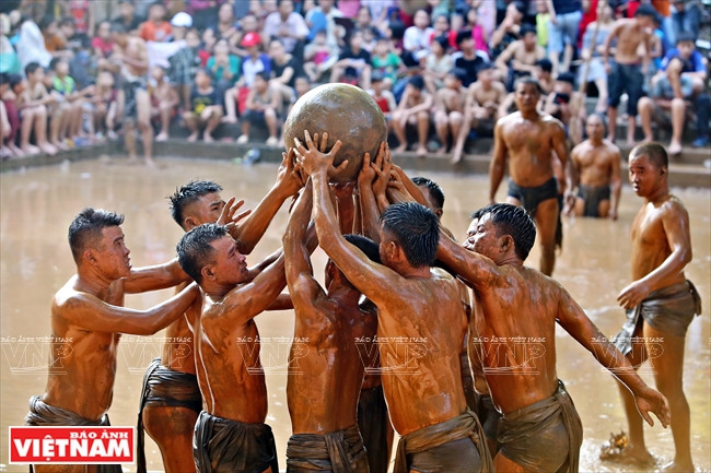 抢到了泥球的一方准备将它投入对方的泥坑。图自越通社