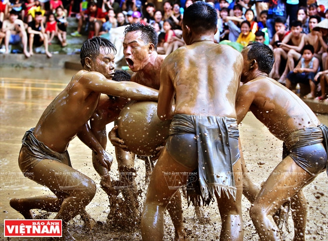 虽被对手包围，甲下队员仍坚持抱住球。图自越通社