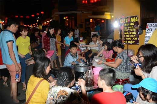 游客在会安古城玲珑灯光下品尝当地美食。（图片来源：人民军队报）