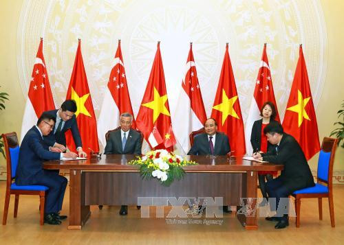 越南政府总理阮春福与新加坡总理李显龙见证越南国有资本投资经营总公司与吉宝置业(越南)有限责任公司之间合作谅解备忘录的签署仪式。（图片来源：越通社）