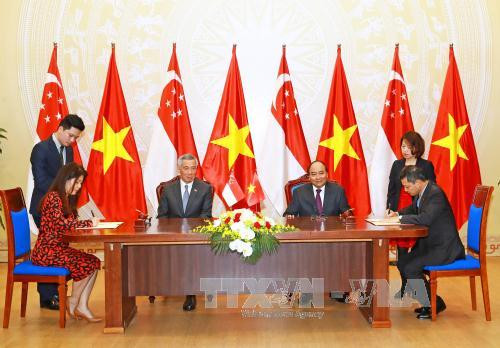 越南政府总理阮春福与新加坡总理李显龙见证新加坡国际基金会与越新友好协会合作备忘录的签署仪式。（图片来源：越通社）