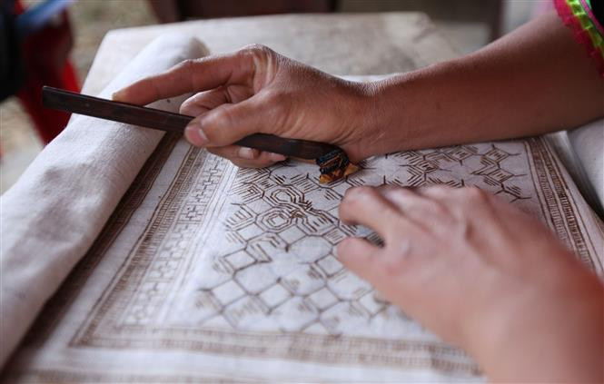  使用蜂蜡在布上画花纹。越通社记者贵忠 摄