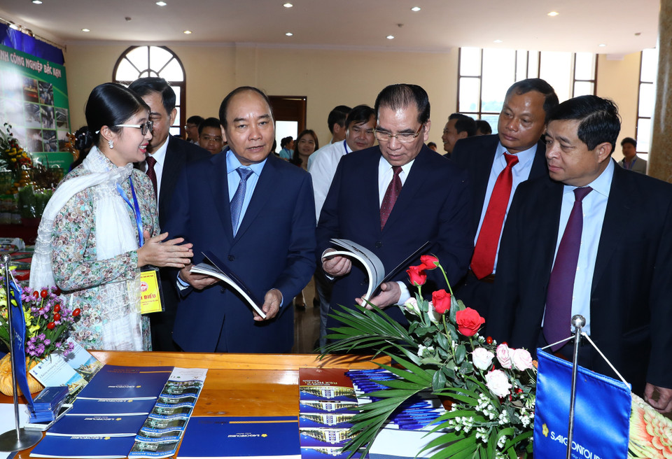  阮春福与各代表参观各展位上展示的产品。（图片来源：越通社）