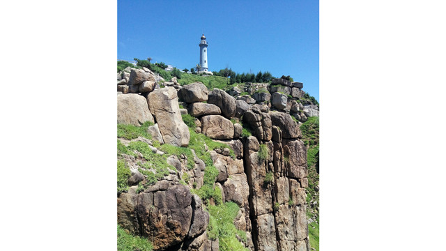 海上灯塔下面的清澈迷人的海阔天空风景以及海岸的雄伟山崖。图自因特网