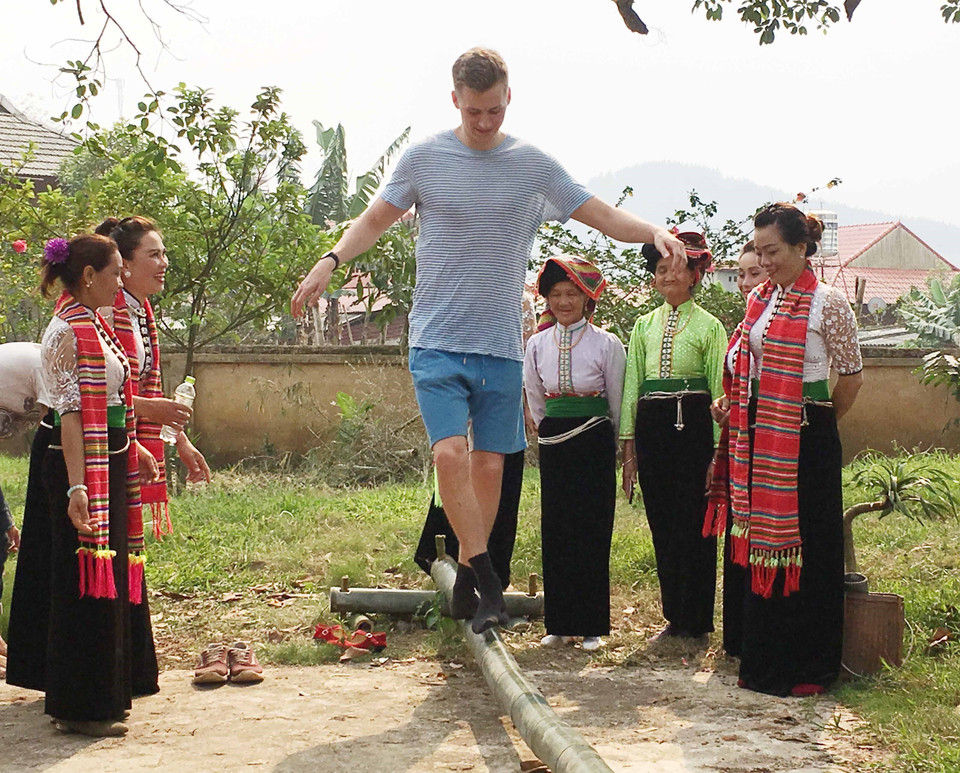 外国游客在傣族感恩节上玩过独木桥游戏。图自越通社