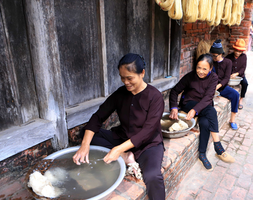 把蚕茧丝纤维煮熟后，用冷水浸泡，然后拉成丝。图自越通社
