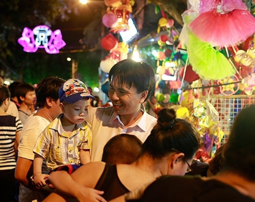 众多家长送小孩上街买来他们喜爱的玩具，快乐赏月。