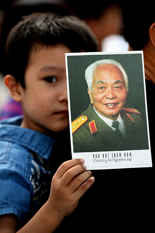 2013年10月，小孩被亲人背在背后排队多时吊唁武元甲大将。（图片来源：《人民报网》）