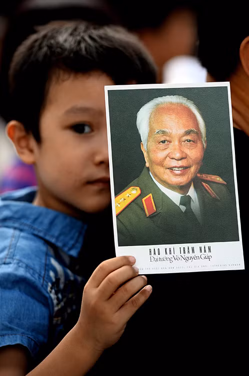 2013年10月，小孩被亲人背在背后排队多时吊唁武元甲大将。（图片来源：《人民报网》）