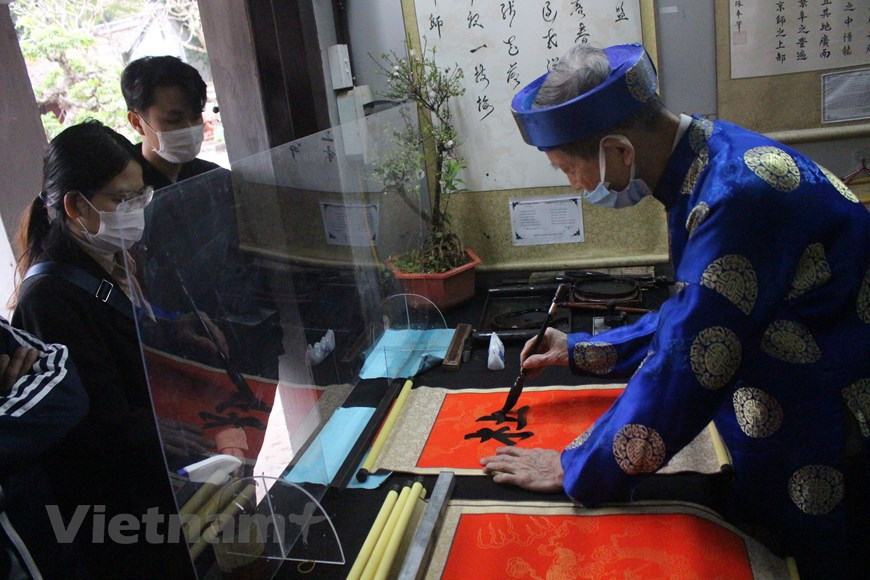 这些大学生刚从老家返回河内。他们选择参观河内各旅游景点，并在文庙求字。在新春佳节的喜庆气氛中，奥黛的五颜六色、红色的宣纸和黑墨的笔画构成一副美丽的画面。拜字、迎字、玩文字、求字、送字是越南人从早就有的优良传统。其中，拜字和迎字是针对皇帝手写的字；而玩文字、求字和送字则是老百姓每逢春节的习俗。图自Vietnam+