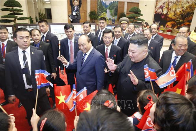 阮春福和金正恩向挥舞越朝两国国旗的孩子们挥手致意。图自越通社