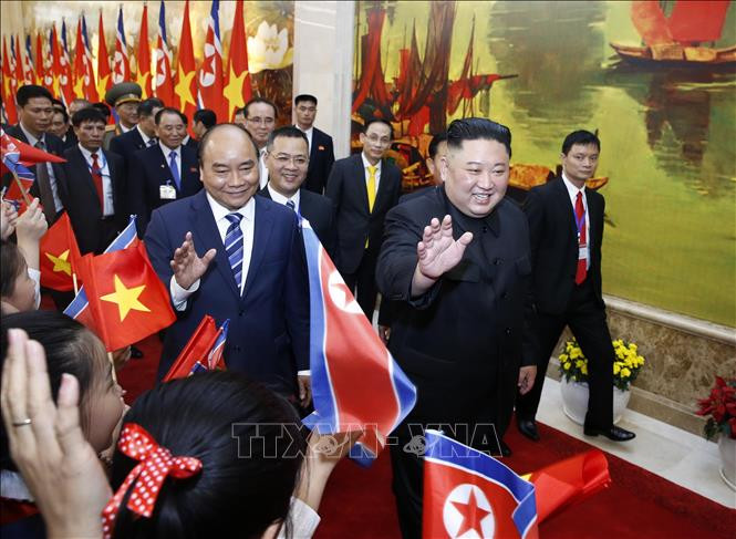 阮春福和金正恩向挥舞越朝两国国旗的孩子们挥手致意。图自越通社