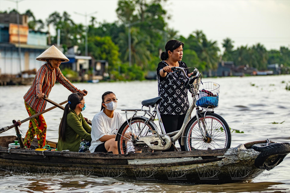 在五叉河口水上集市上，摆渡人将两岸的学生和居民运送过河。图自越通社/《越南画报》